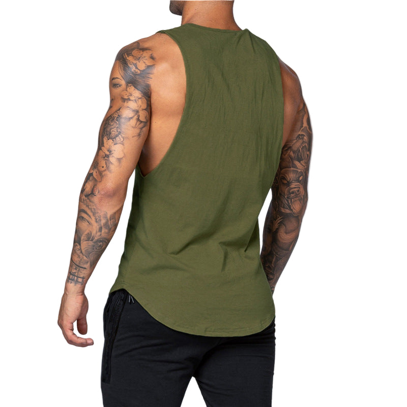 Person wearing an olive green tank top with tattoos on arms against a light gray background