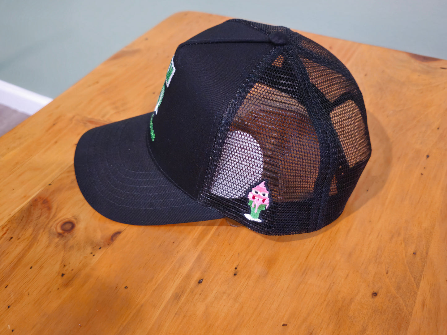Black mesh cap with floral design on a wooden surface