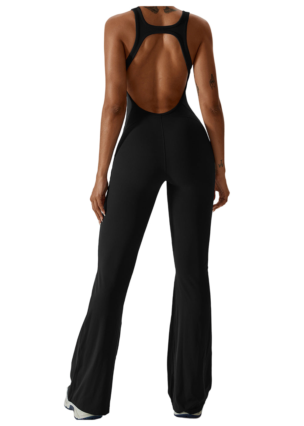 Person wearing a black open-back jumpsuit on a white background