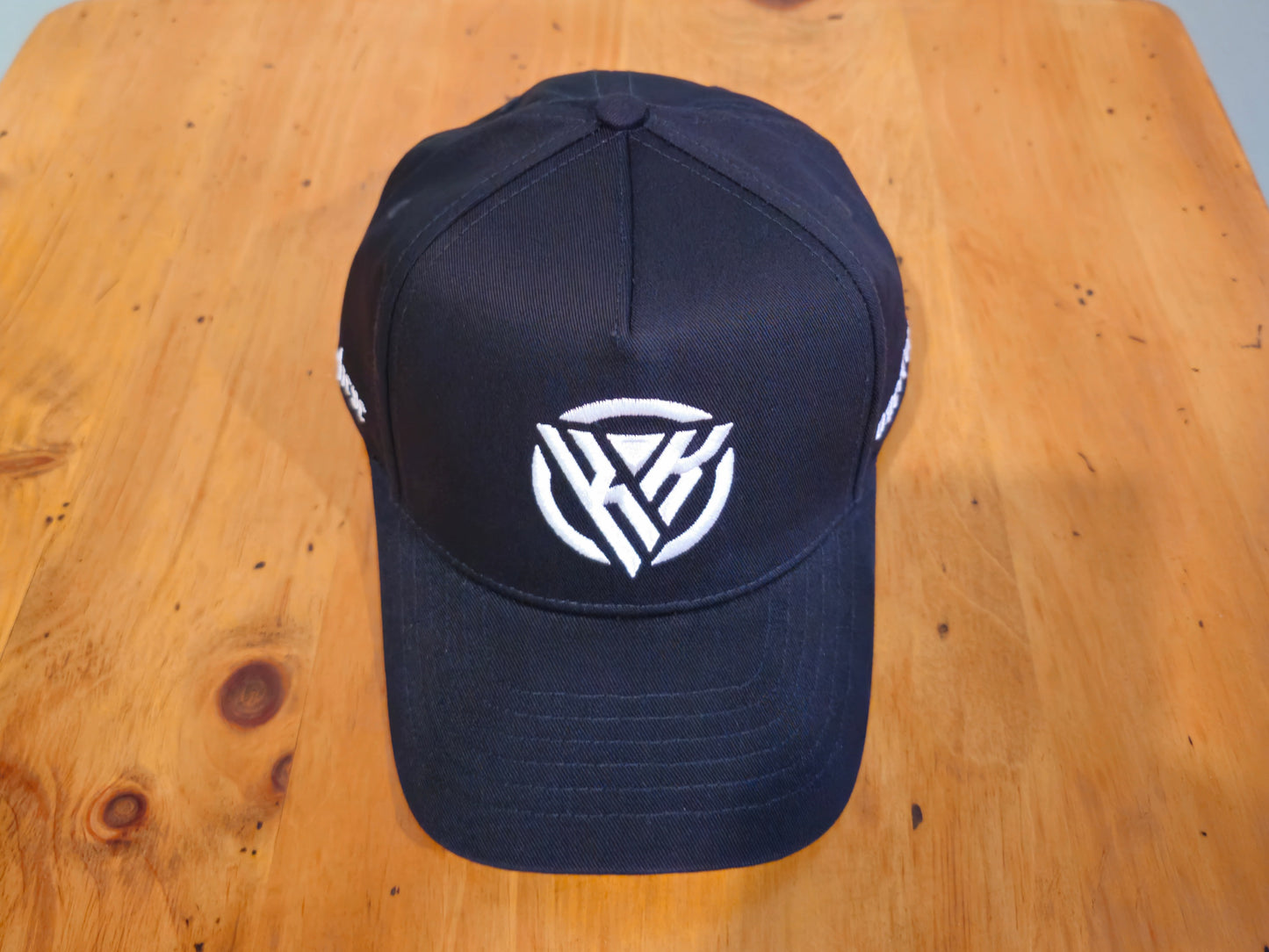 Black cap with a white logo on a wooden surface