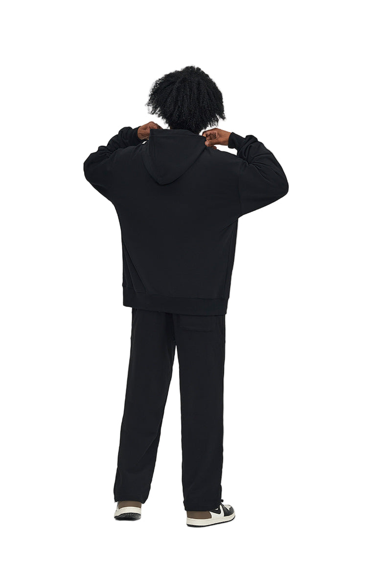 Person wearing a black hoodie and pants on a white background