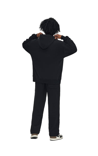 Person wearing a black hoodie and pants on a white background