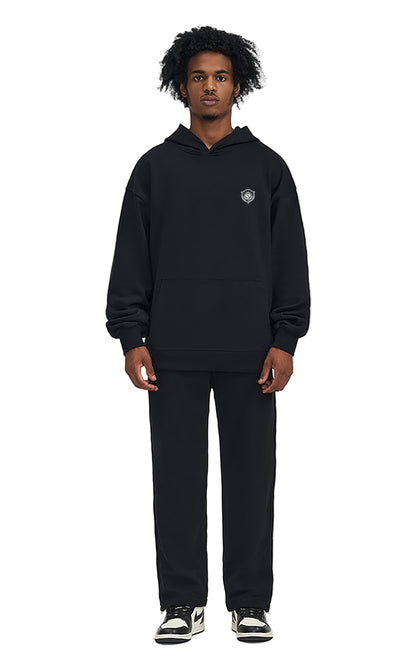 Person wearing a black hoodie and pants on a white background