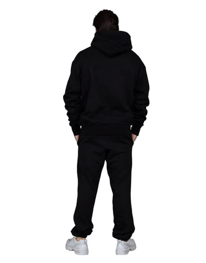 Person wearing a black hoodie and pants with white sneakers on a gray background