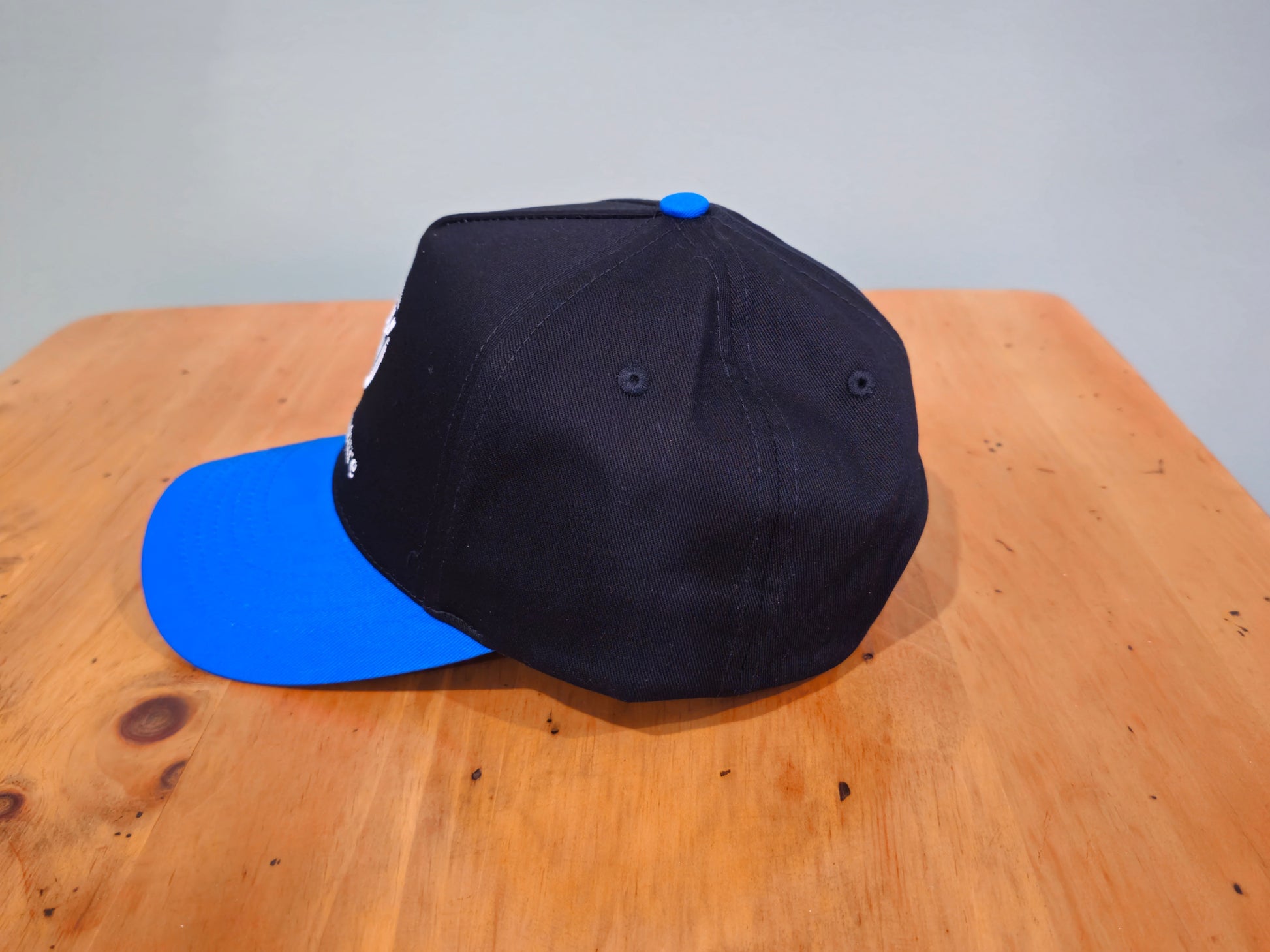 Black cap with blue brim on a wooden surface