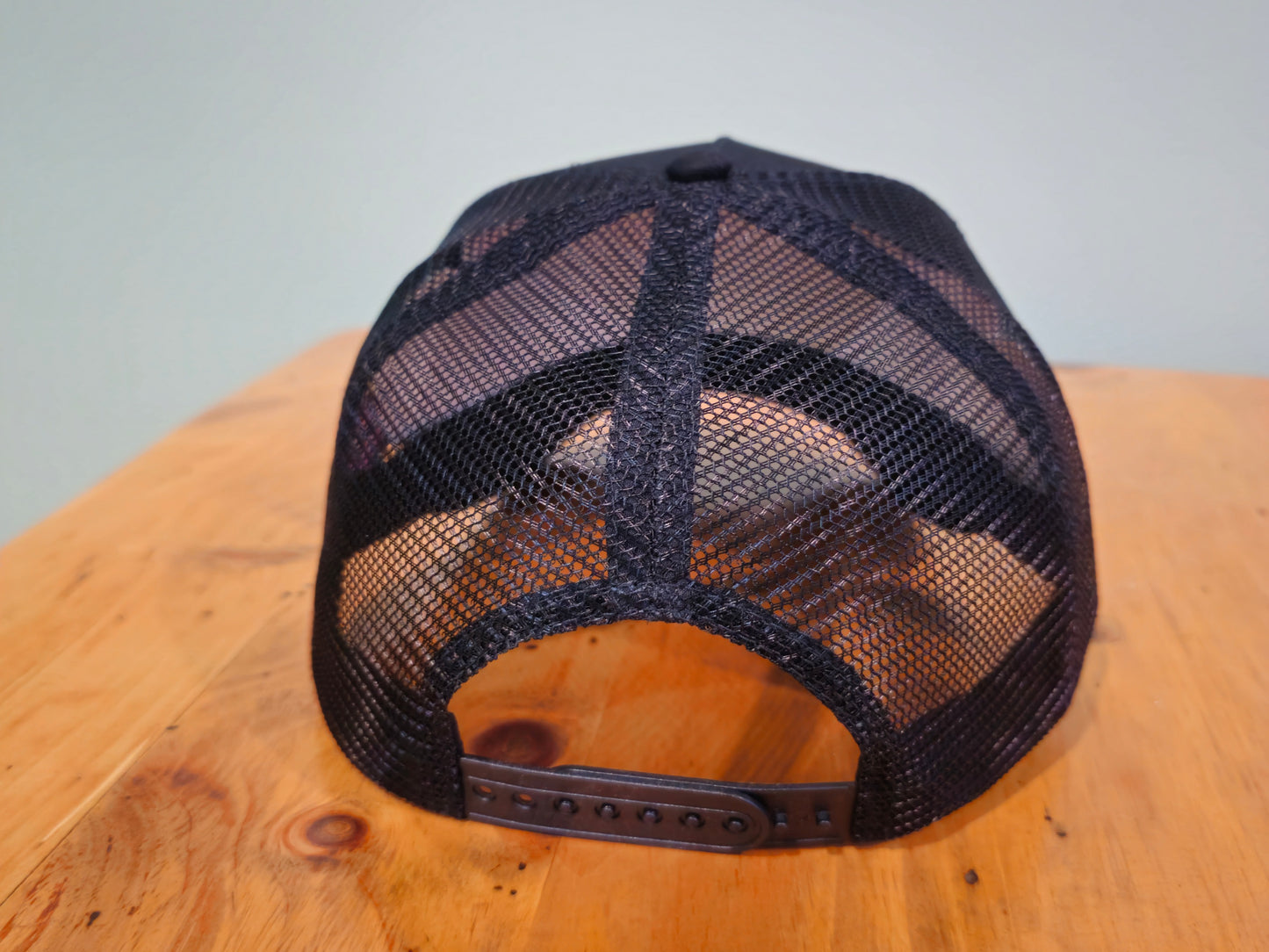 Black mesh cap on a wooden surface with a light gray background