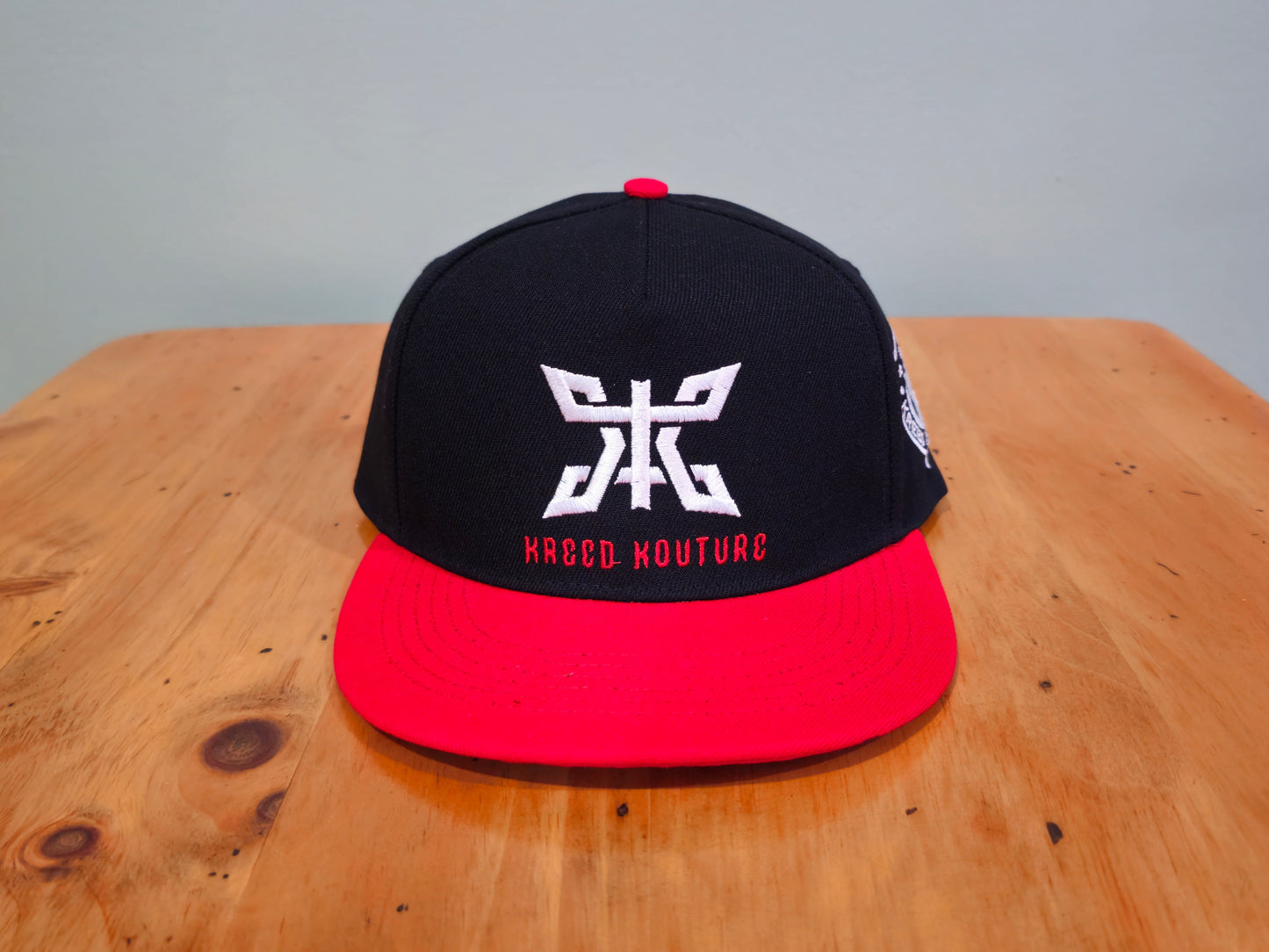 Black and red cap with a logo on a wooden surface