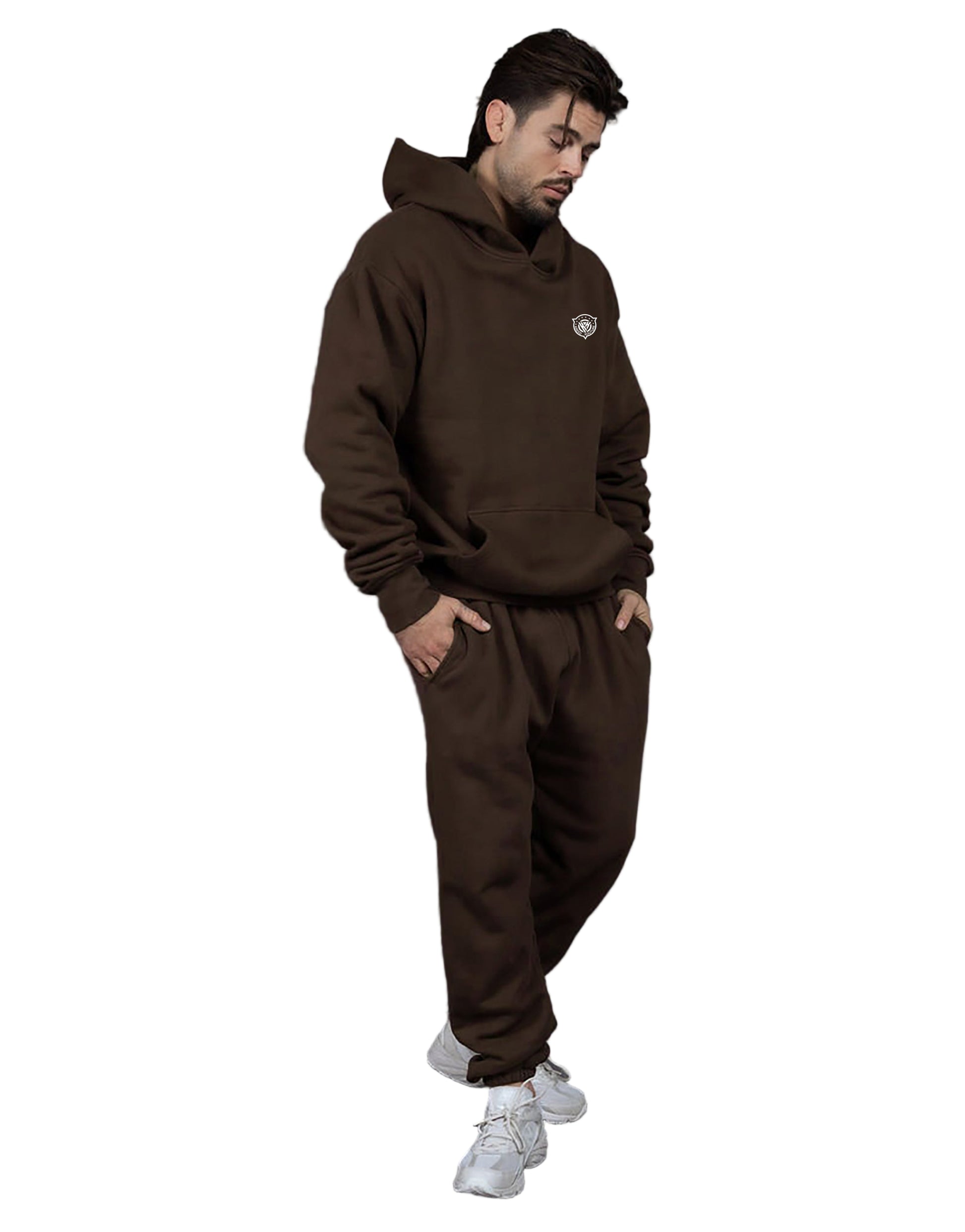 Man wearing a brown hoodie and pants with a small logo, standing against a gray background
