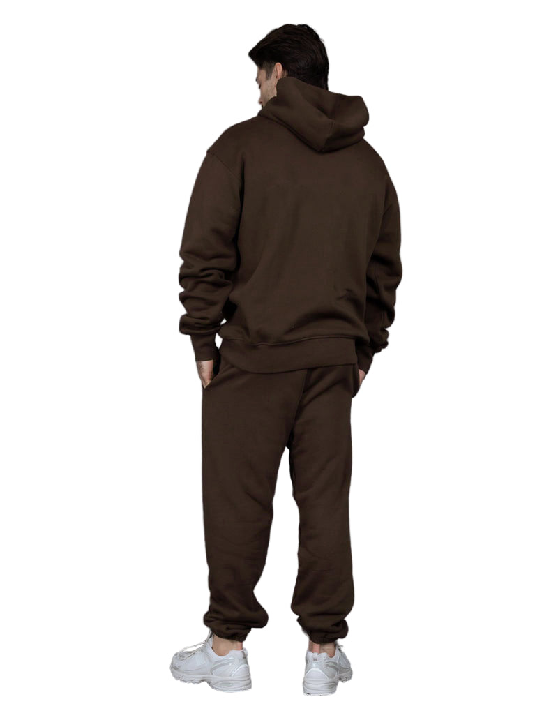 Person wearing a brown tracksuit against a gray background