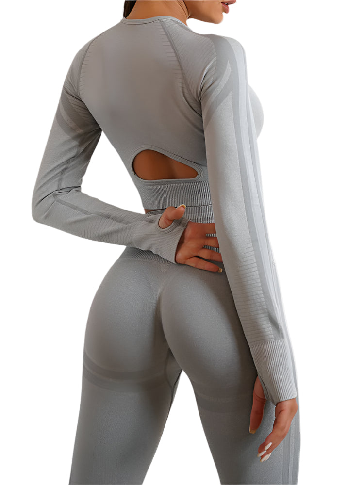 Person wearing a gray long-sleeve top and leggings with cut-out design on a plain background