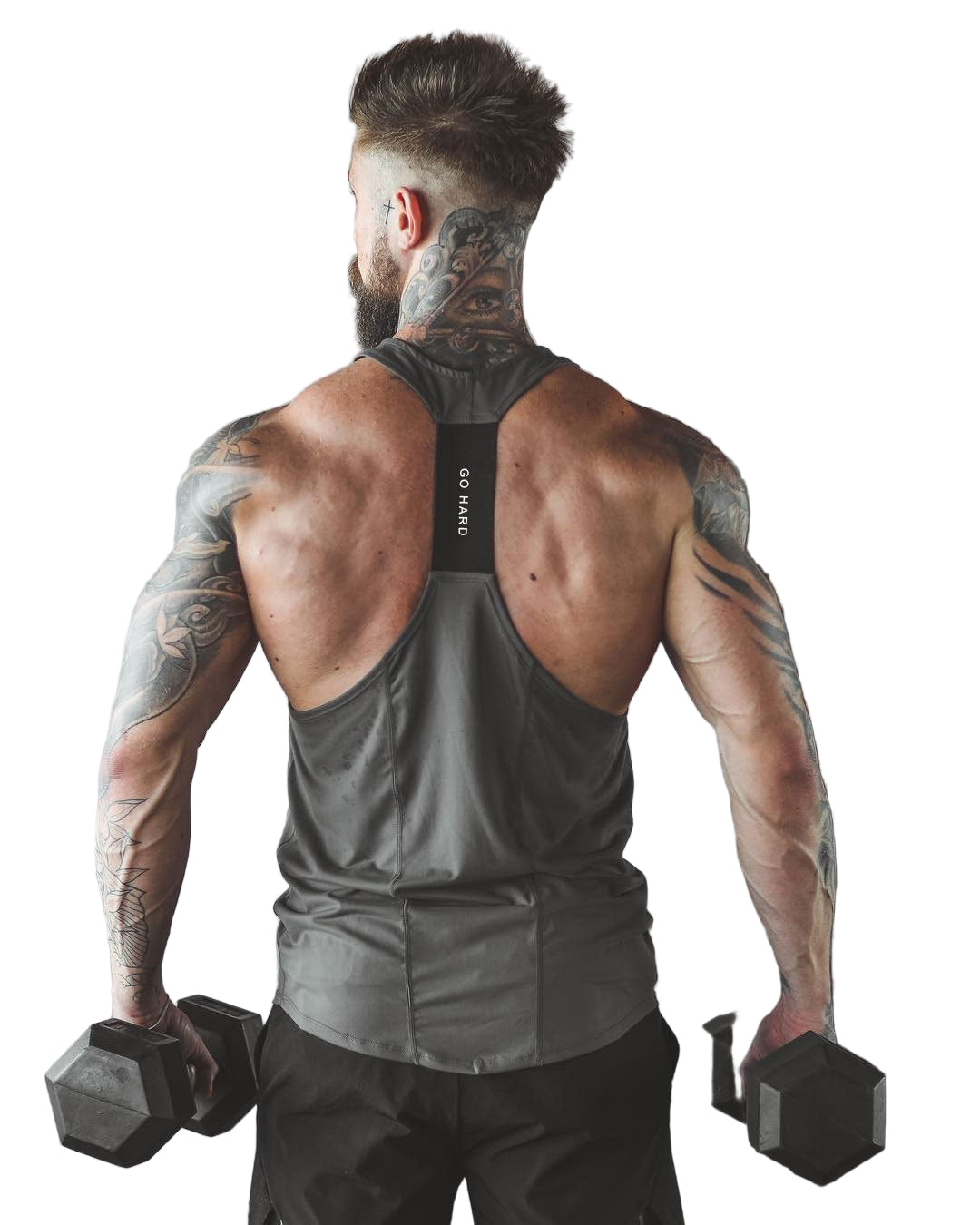 Muscular man with tattoos holding dumbbells in a gym setting