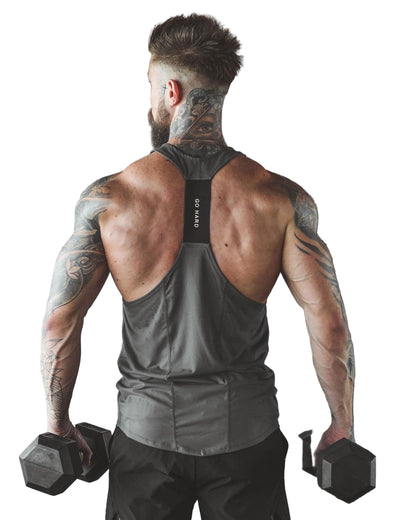 Muscular man with tattoos holding dumbbells in a gym setting