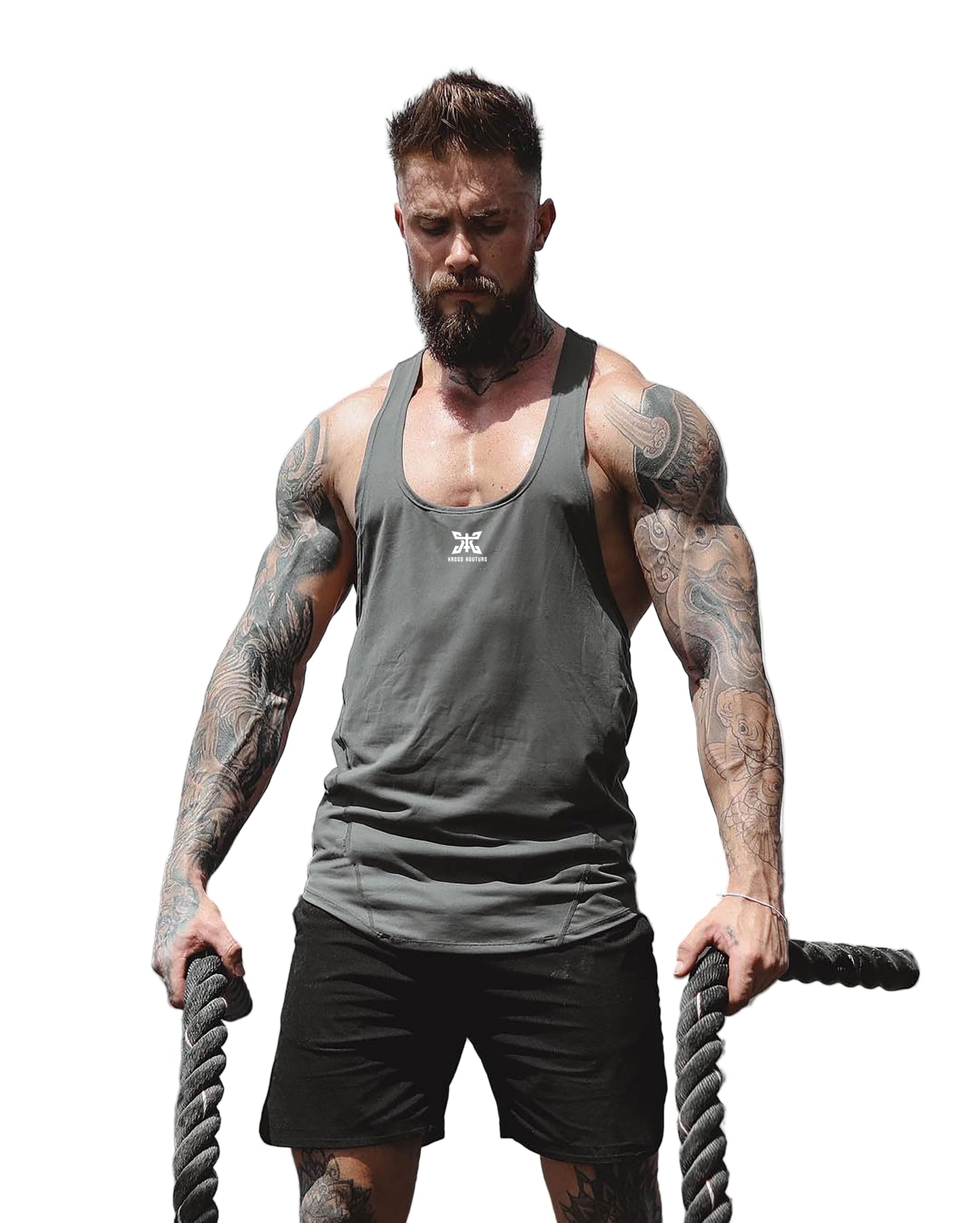 Man with tattoos holding battle ropes against a light background