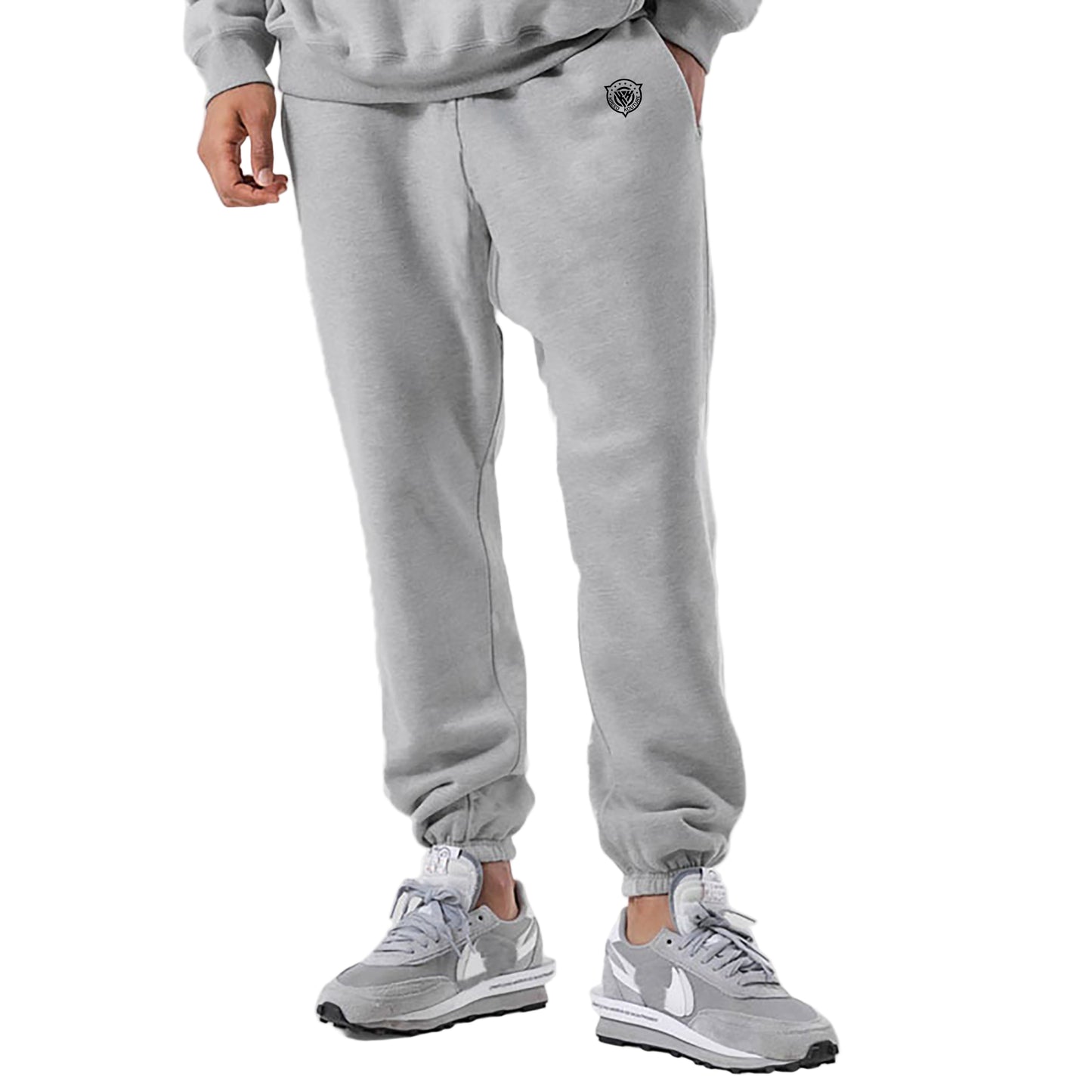 Person wearing gray sweatpants and matching sneakers on a light gray background