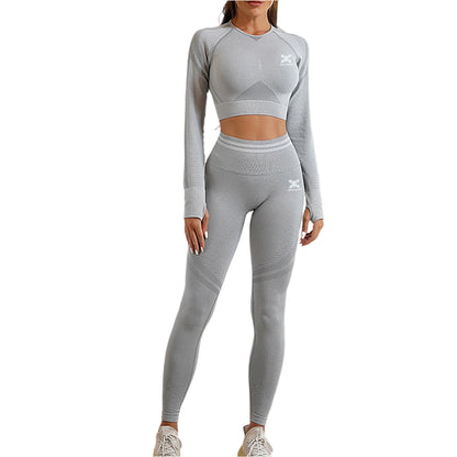 Person wearing a gray athletic outfit with a logo on a plain background