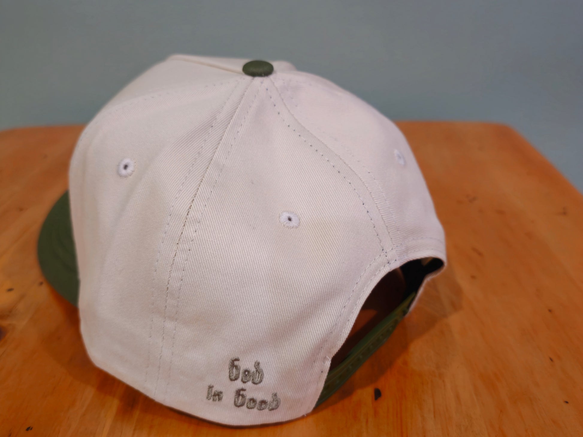 Beige cap with green brim on a wooden surface