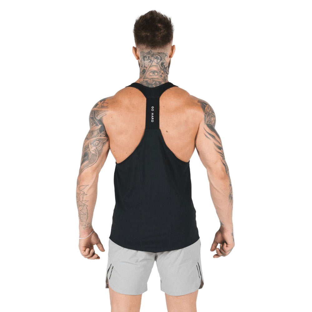 Man wearing a black tank top and gray shorts on a white background